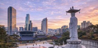 Korean Temples ① Bongeunsa Bongeunsa Temple courtyard and standing Buddha statue with the Gangnam skyline at sunset in Seoul
