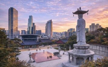 Korean Temples ① Bongeunsa Bongeunsa Temple courtyard and standing Buddha statue with the Gangnam skyline at sunset in Seoul