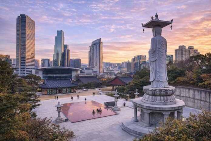 Bongeunsa Temple courtyard and standing Buddha statue with the Gangnam skyline at sunset in Seoul