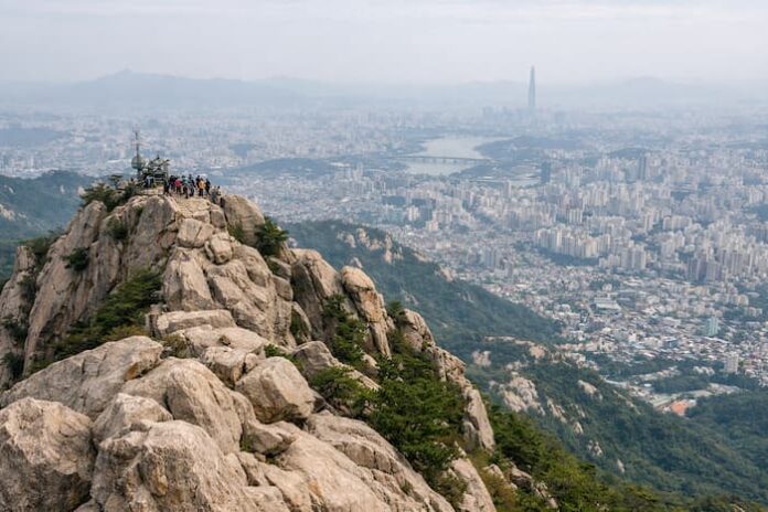 ChatGPT Image 2026년 4월 16일 오후 12_53_42 Rocky summit view of Gwanaksan overlooking Seoul on a hazy day