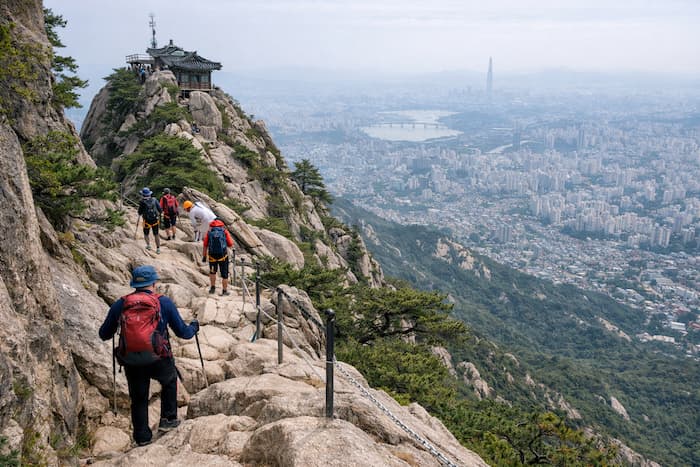 Hikers ascending a steep rocky trail on Gwanaksan Mountain