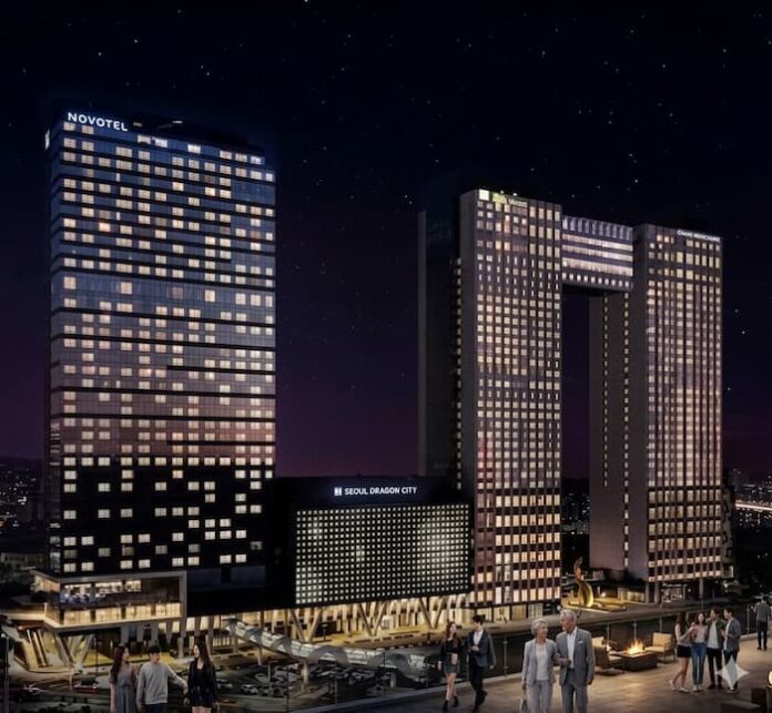 밤하늘 아래 조명이 빛나는 서울드래곤시티의 현대적인 트윈 타워와 노보텔 앰배서더 건물 전경.