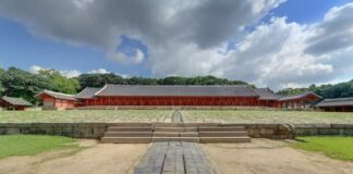Wide front-facing photograph of Jeongjeon Hall at Jongmyo Shrine in Seoul with its broad stone courtyard and central ceremonial path