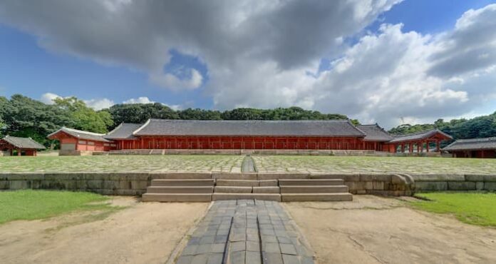 Wide front-facing photograph of Jeongjeon Hall at Jongmyo Shrine in Seoul with its broad stone courtyard and central ceremonial path